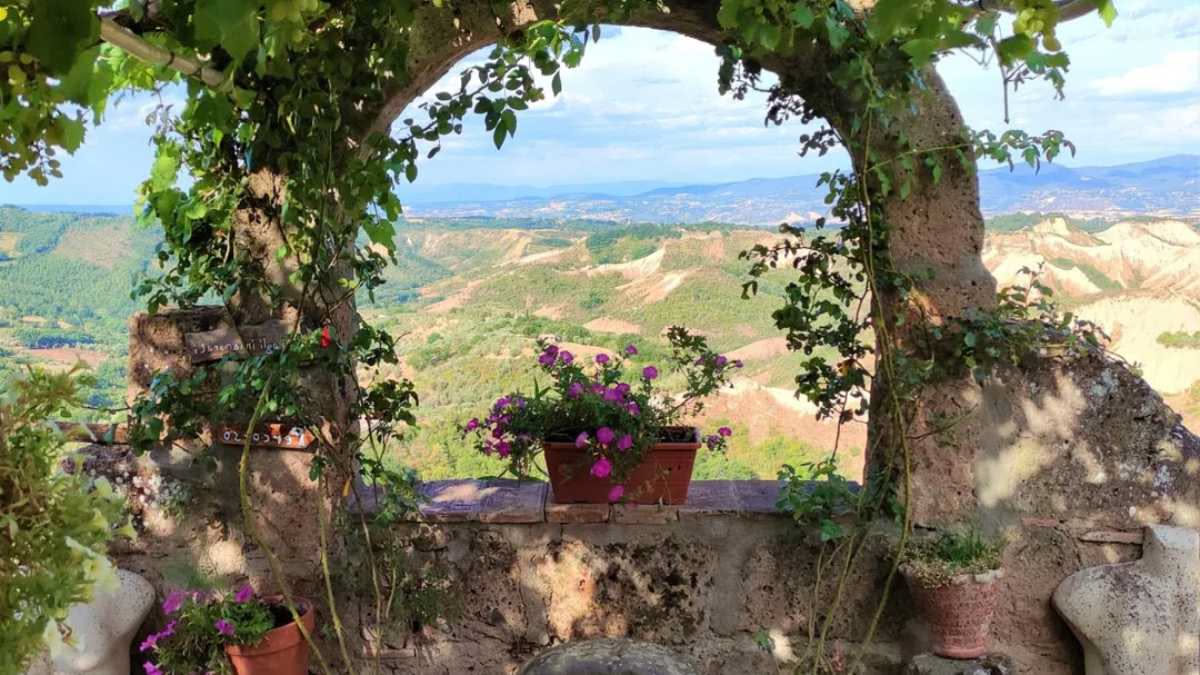 Donna che si prende cura delle piante in un giardino rigoglioso, circondata da fiori colorati e spazi verdi terapeutici per il benessere.