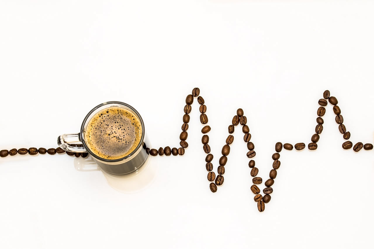 Tazza di caffè fumante con chicchi di caffè sparsi su un piano di legno, simbolo dei benefici scientificamente provati della bevanda