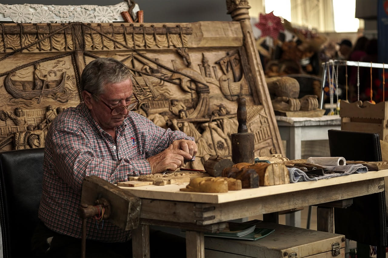 Maestro artigiano al lavoro in una bottega storica fiorentina, intento a lavorare il legno con attrezzi tradizionali tra muri antichi e opere d'arte