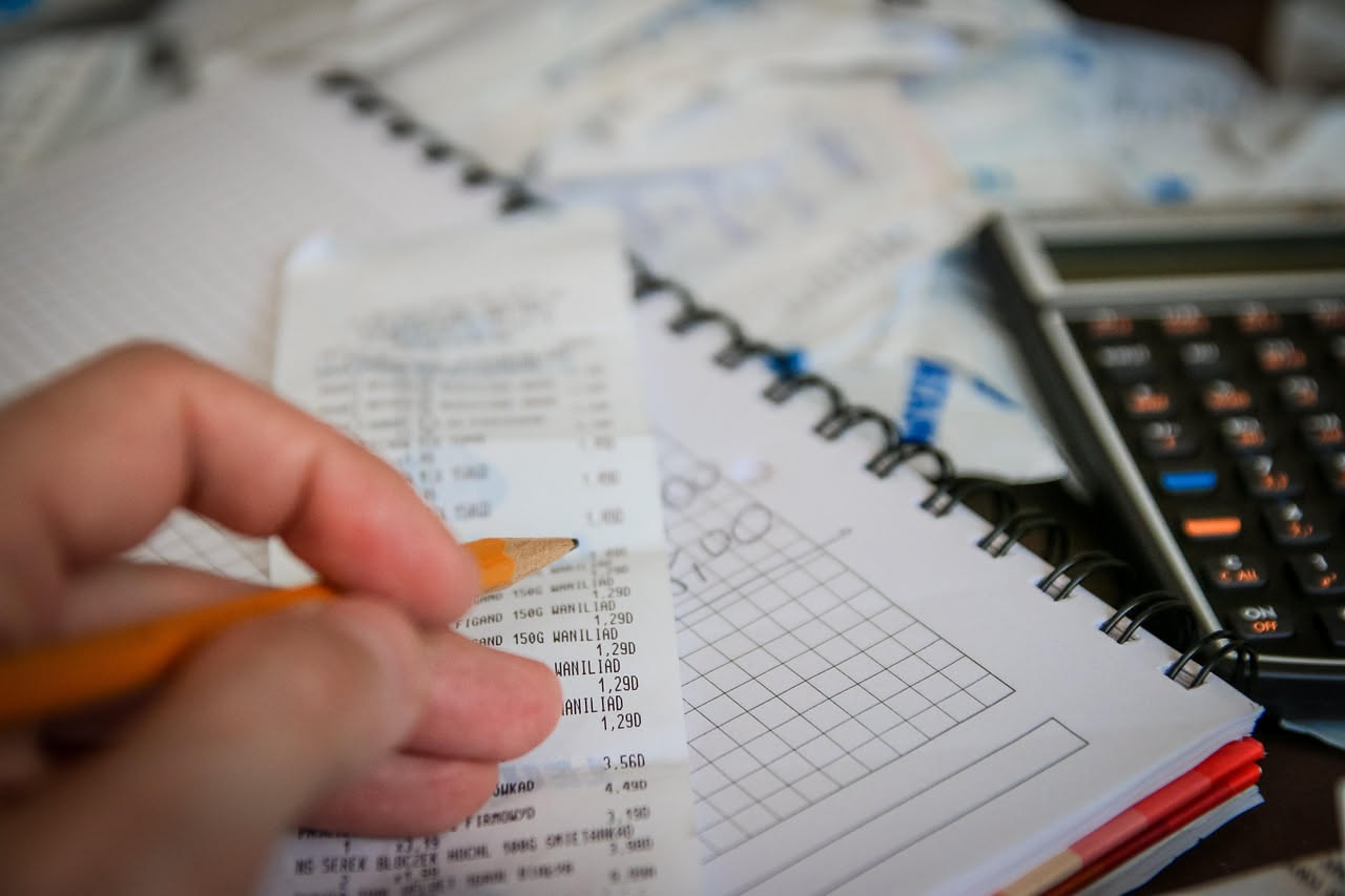 Famiglia che pianifica il budget attorno a un tavolo con foglio di calcolo, matita e calcolatrice per gestire le spese domestiche mensili