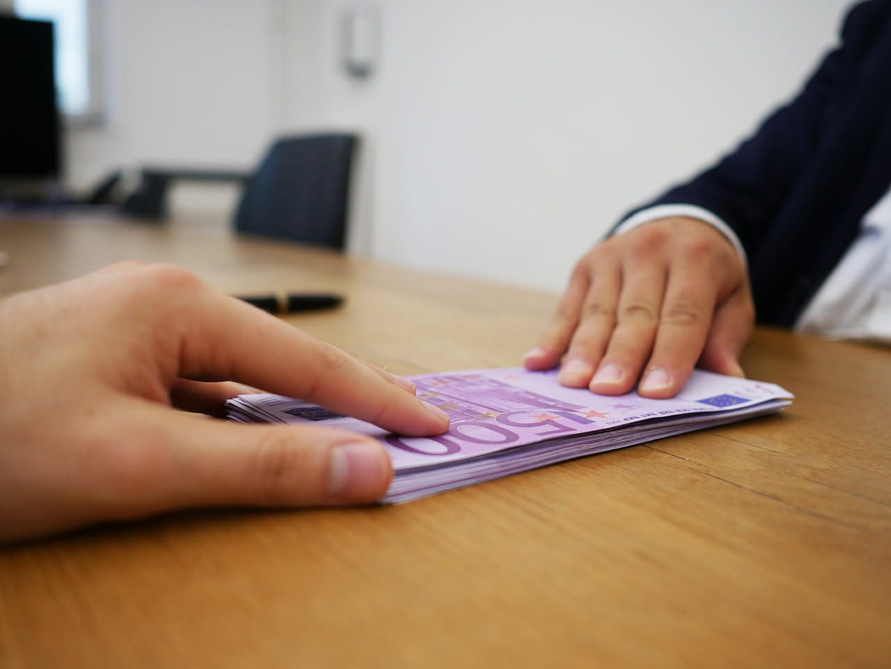 Professionista in colloquio di negoziazione stipendio con dirigente in ufficio moderno, documenti e grafici retributivi sulla scrivania