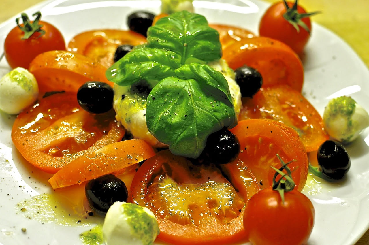 Piramide alimentare della dieta mediterranea con frutta, verdura, cereali integrali, olio d'oliva e pesce su sfondo bianco