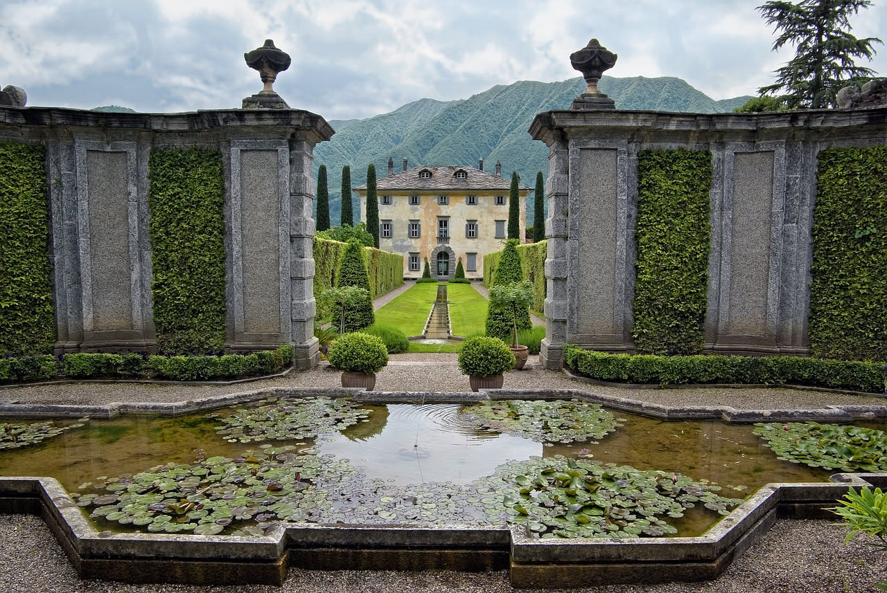 Giardini terrazzati della Villa del Balbianello con azalee in fiore, rose antiche e viste panoramiche sul lago di Como circondato da montagne