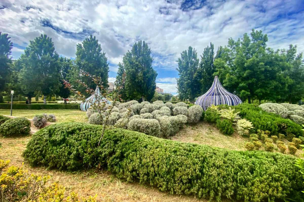 Veduta aerea del Giardino dei Tarocchi di Capalbio con sculture colorate, piante verdi, viali sinuosi e cielo sereno della Toscana