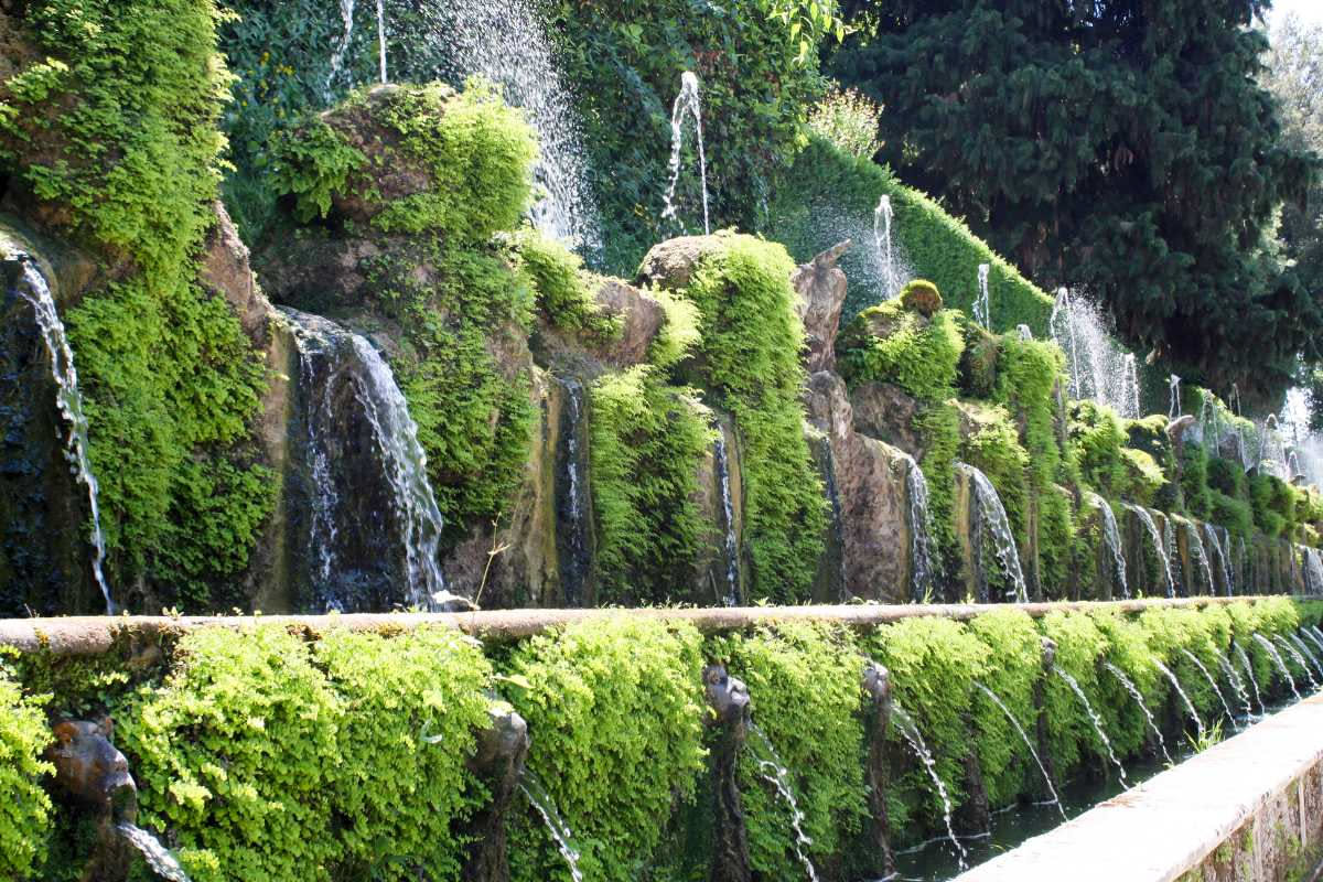 Fontana monumentale di Villa d Este con cascate d'acqua multiple, statue in travertino, cipressi verdi e visitatori lungo il percorso del giardino rinascimentale