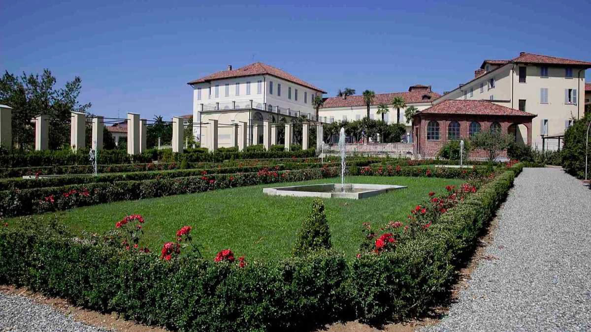 Roseto Comunale di Roma con rose rosse, bianche e rosa che fioriscono su terrazze degradanti verso il Circo Massimo, muri di pietra antica e pergolati verdi sotto il sole