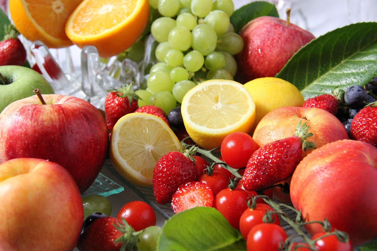 Vassoio con fette di anguria, melone retato, pesche e fragole fresche appena tagliate su un tavolo in giardino all'ombra, in una giornata estiva